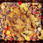 Baking sheet of roasted vegetables and a roasted chicken.