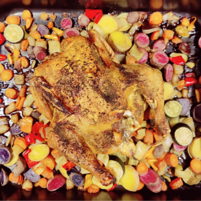 Baking sheet of roasted vegetables and a roasted chicken.