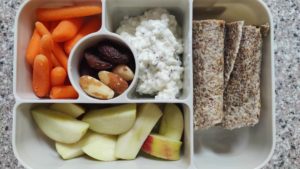 Bento box with cottage cheese, tempeh and avocado wrap, apples, carrots and brazil nuts.