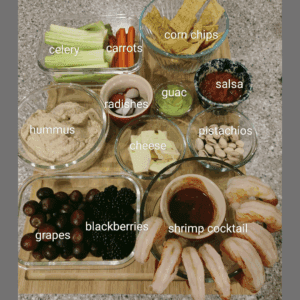 healthful snack board with various fruits, veggies, shrimp, cheese, nuts, etc.